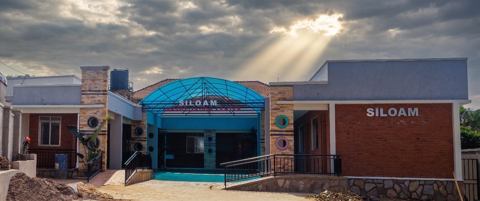 The Siloam Rehabilitation Centre building in Uganda at sunrise, with its blue arched entrance canopy